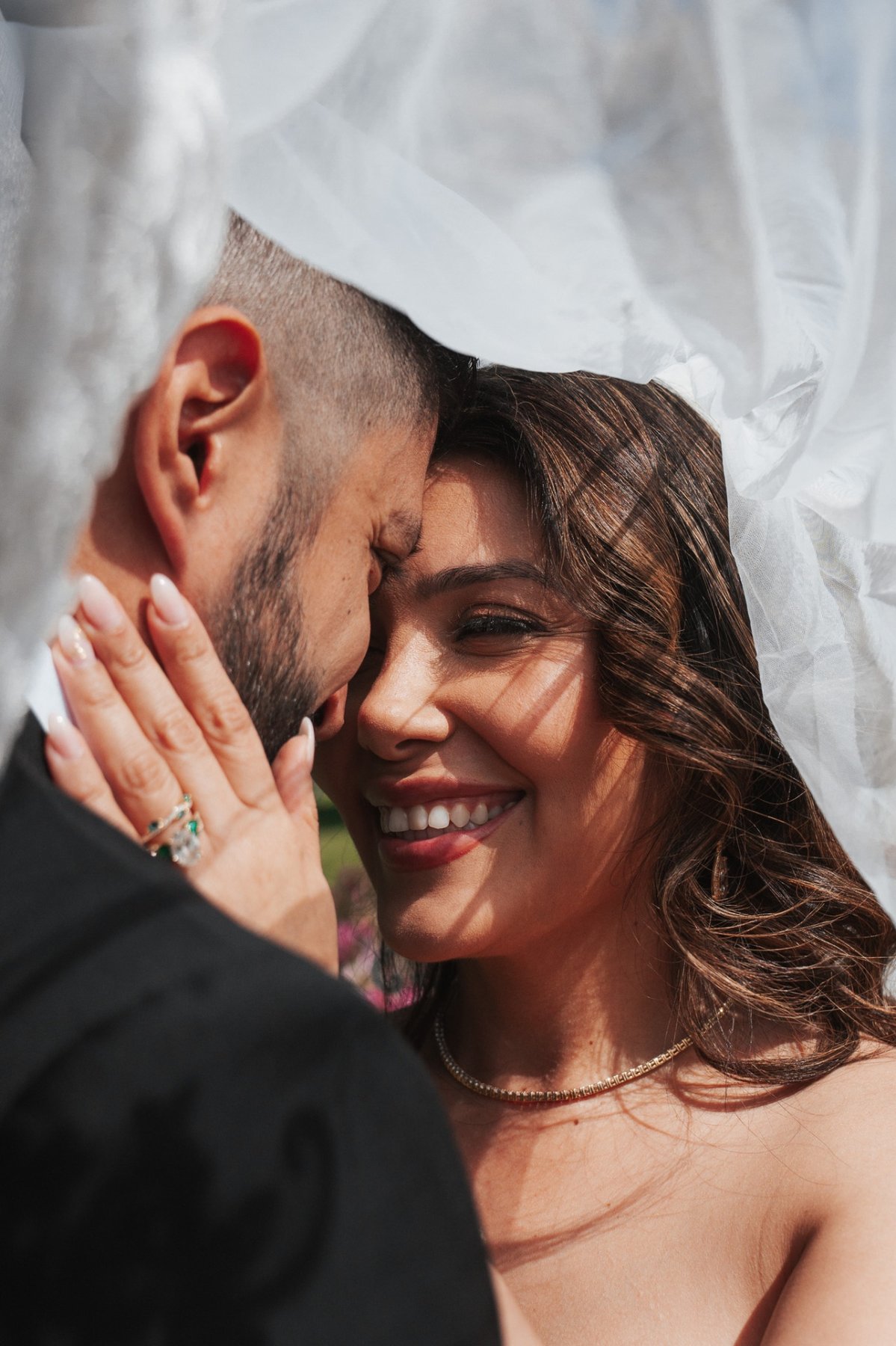 Bride smiling under the veil in golden sunlight