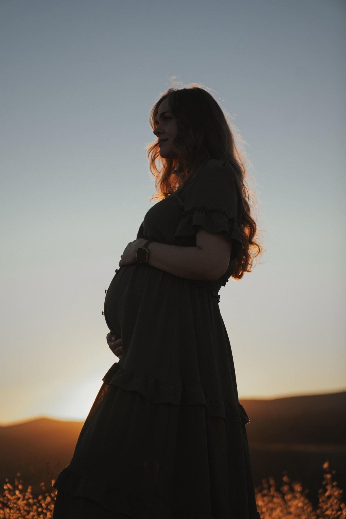 Silhouette of an expecting mother at sunset