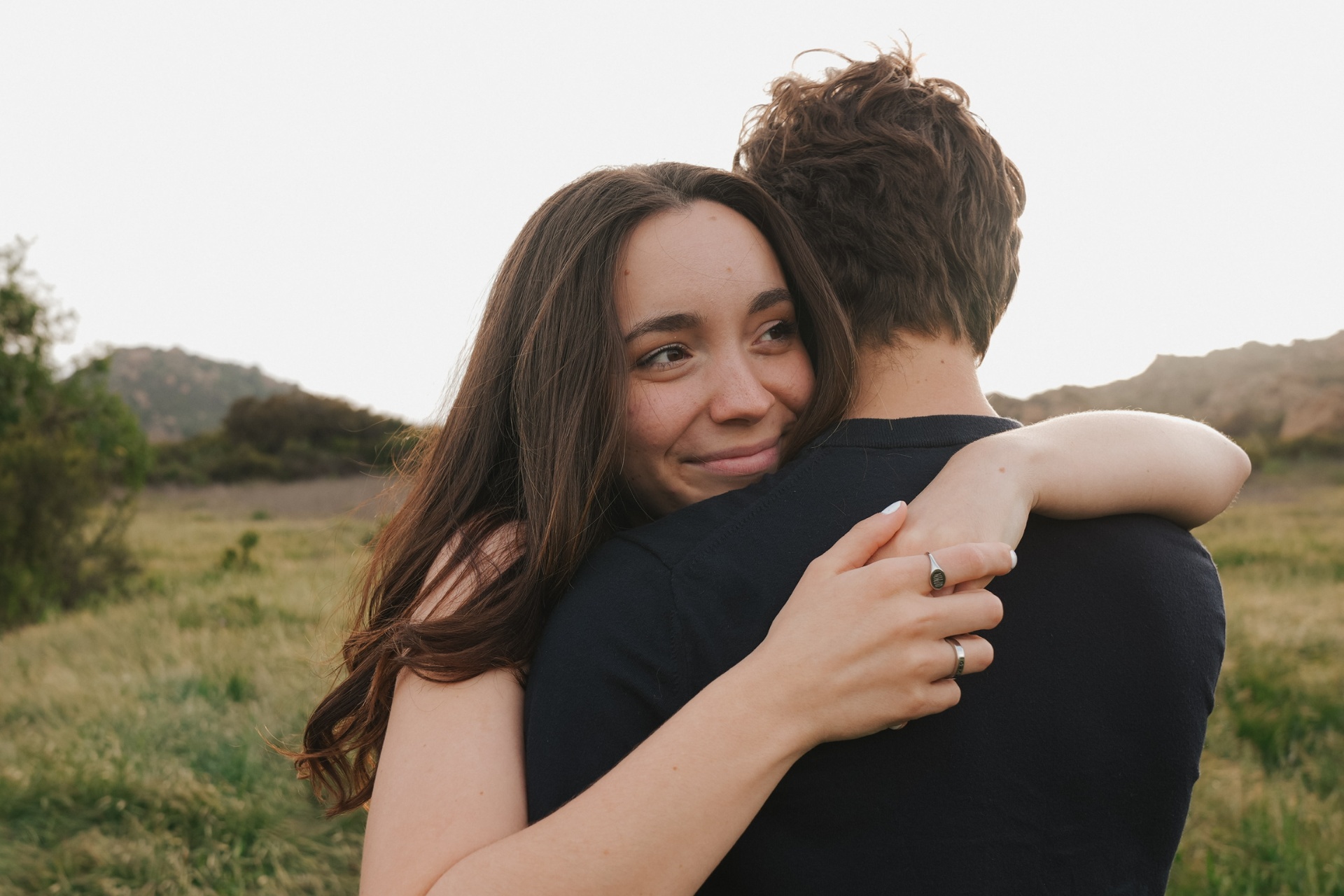 Couple hugging in a golden field, smiling over the shoulder