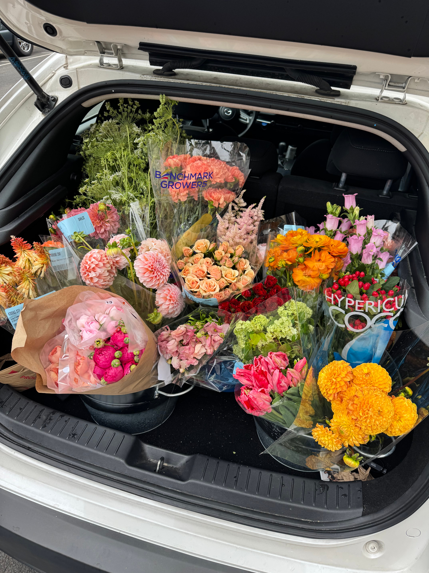 Vibrant centerpiece of dahlias, ranunculus, and garden roses in coral and orange tones