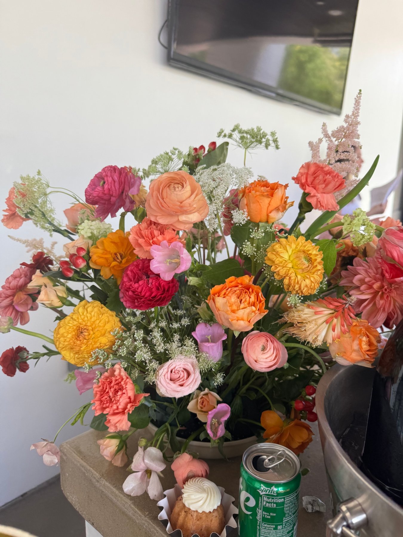Vibrant arrangement of ranunculus, roses, and carnations in coral, orange, and pink